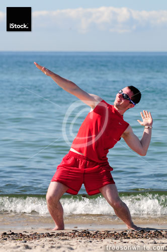 Surfer dude exercising on the beach in red swim suit.