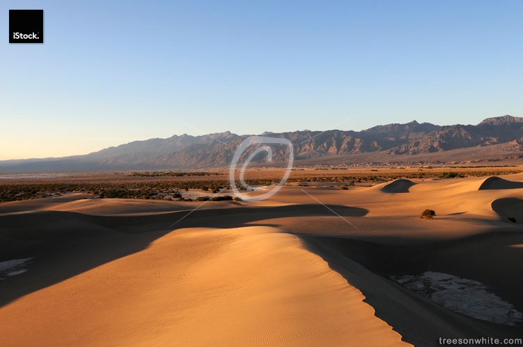 Death Valley at sunset with dunes and desert mountains.