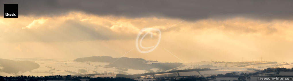 Winter landscape with warm sunrays piercing a cloudy sky (German