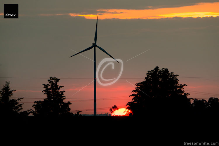 Sun setting down behind Wind turbine and electricity lines.
